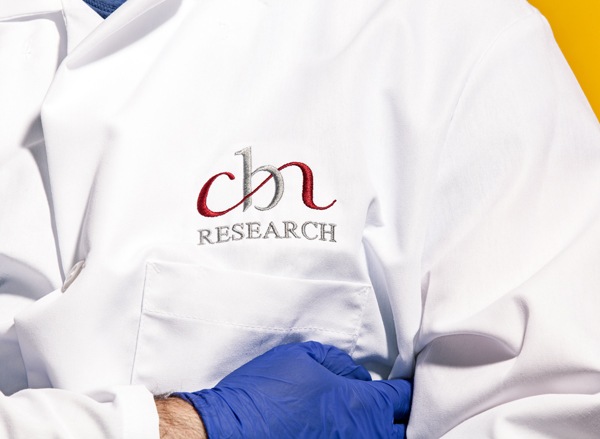 Part of CBN employees lab coat with 'CBN Research' embroidered on it